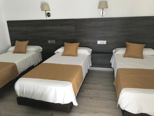 a room with three beds with brown and white sheets at Hotel Restaurante Santa Cruz in Santa Cruz de Mudela