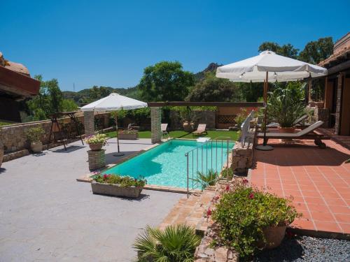 une piscine avec un parasol et un patio dans l'établissement Antico Casale del Poggio, à Capoterra