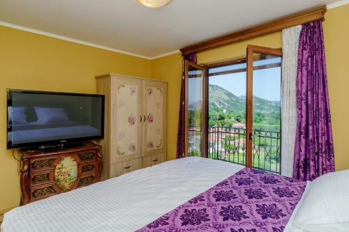 a bedroom with a bed and a tv and a balcony at RUSTIC HOUSE LEKOVIĆ in Virpazar