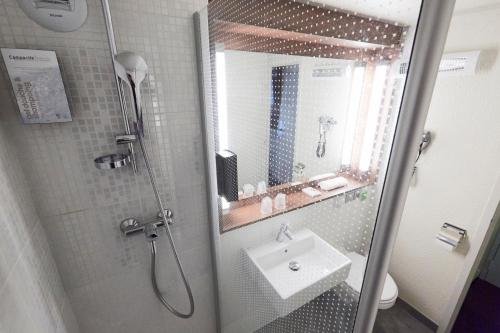 a bathroom with a shower with a sink and a mirror at Campanile Epinay sur Orge Savigny Sur Orge in Épinay-sur-Orge