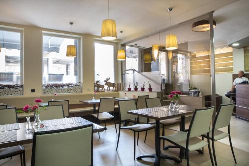 um restaurante com mesas, cadeiras e janelas em Garni Hotel Zenit em Novi Sad