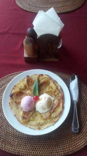 a plate of pancakes with ice cream on a table at Maha Neka Villa in Sidemen