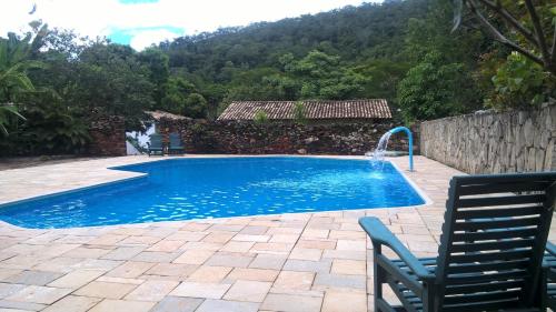 a swimming pool with two chairs and a water fountain at Pousada do Ipe in Goiás