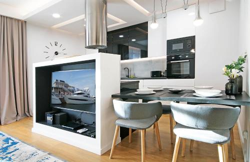 a kitchen with a dining table with chairs and a fireplace at IRS ROYAL APARTMENTS Apartamenty IRS Neptun Park in Gdańsk