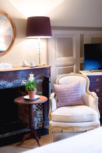 a living room with a chair and a mirror at Le Manoir des Impressionnistes - Bord de Mer in Honfleur