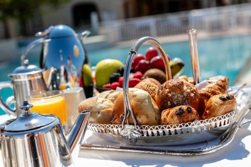 ポルティシオにあるHotel Le Maquisの- ペストリーとフルーツのバスケット(テーブルの上)