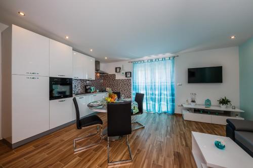 Una cocina y sala de estar con gabinetes blancos y una mesa. en Lavender & Mint, en Kaštela