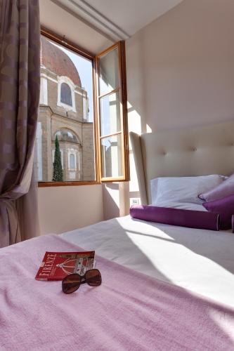 a pair of glasses sitting on a bed with a window at Solo Experience Hotel in Florence