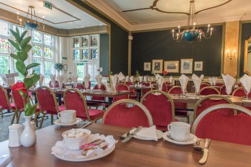 a dining room with tables and red chairs at Cairn Hotel in Harrogate