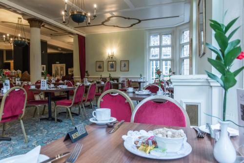 a dining room with pink chairs and tables at Cairn Hotel in Harrogate