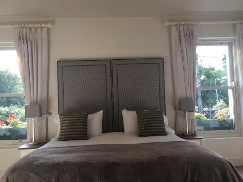 a bedroom with a large bed with two windows at Horse & Hound in Delgany