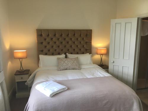 a bedroom with a large white bed with two lamps at Horse & Hound in Delgany