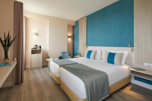 a hotel room with a large bed and a blue wall at Occidental Faro in Faro