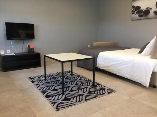 a room with a bed and a table on a rug at Rentalis Flat in Liège