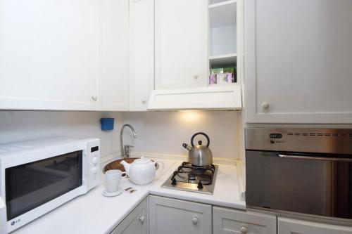 a white kitchen with white cabinets and a microwave at Frattina Apartments in Rome