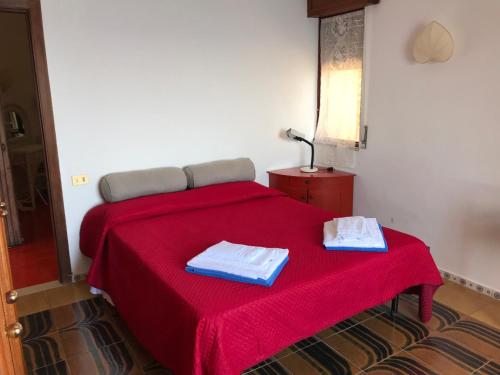 um quarto com uma cama vermelha com duas toalhas em Villa Mariedda em Taormina