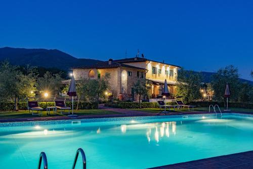 a large swimming pool in front of a house at night at Savernano in Reggello