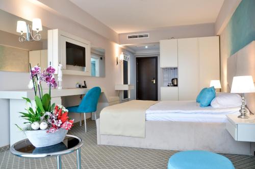 沃萊尼德蒙泰的住宿－Hotel Afrodita -Valenii De Munte，配有床和鲜花桌的酒店客房