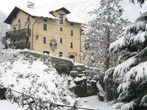 アオスタにあるHotel Cecchinの雪に覆われた木の前の建物