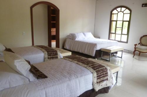 a hotel room with two beds and a chair at Villa de los Angeles in Medellín