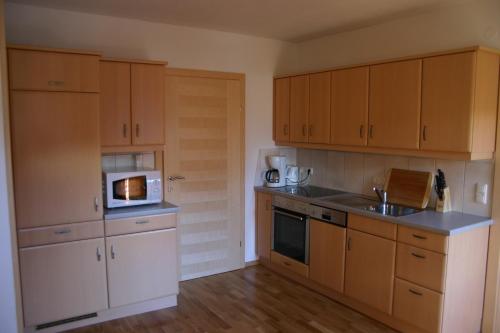 a kitchen with wooden cabinets and a microwave at Stallerhof in Hüttschlag
