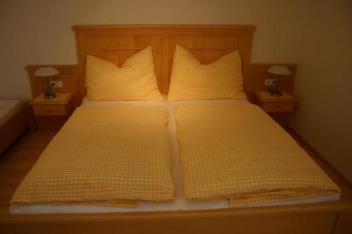 a bed with yellow and white checkered pillows at Stallerhof in Hüttschlag