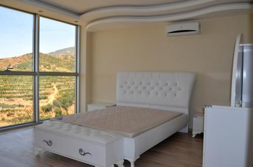 a bedroom with a white bed with a large window at panaroma villaları in Alanya