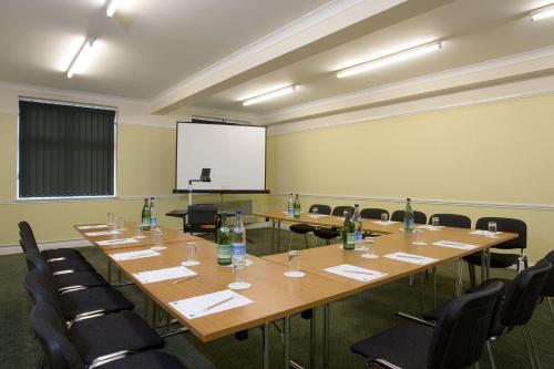 a conference room with tables and chairs and a screen at Best Western Thurrock Hotel in Grays Thurrock