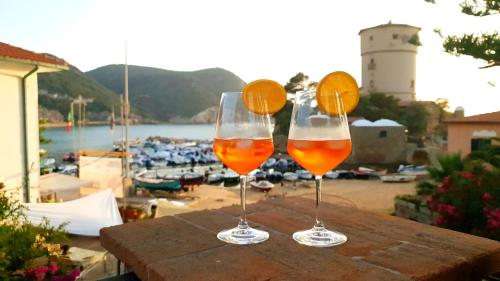 two wine glasses sitting on a table with a view of a harbor at Hotel Giardino delle Palme in Campese