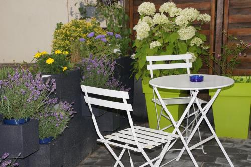 two white chairs and a table and some flowers at Logis Hotel Epi d'Or in Angoulême