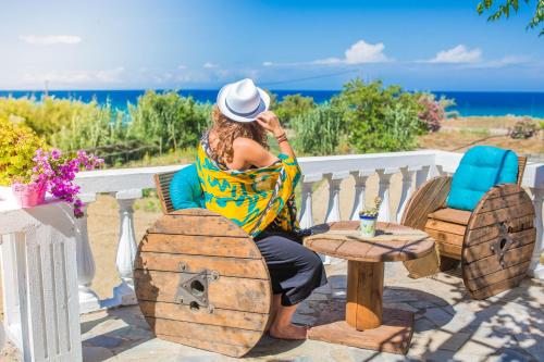 a woman sitting on a bench looking at the ocean at Ammos Apartments in Alikanas