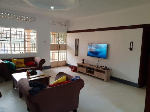 a living room with two couches and a flat screen tv at Banda Lodge in Masaka