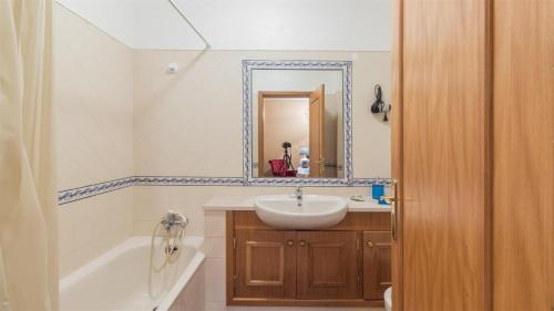 Un baño con lavabo, bañera y espejo. en Amoreira Mar IV Alvor, en Alvor