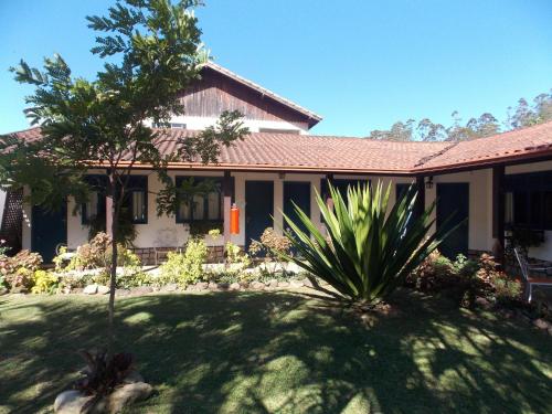una casa con un patio de hierba delante de ella en Pousada Canto Nosso en São Pedro da Serra
