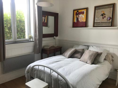 une chambre avec un lit avec des draps blancs et des oreillers dans l'établissement La Fantaisie, à Villers-sur-Mer