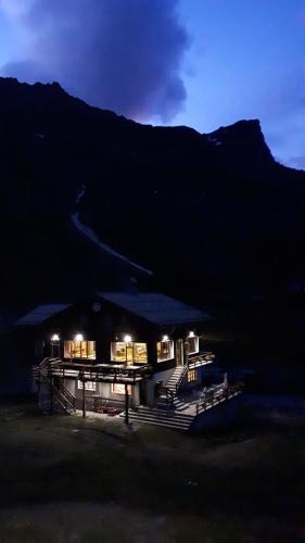 a building with lights in front of a mountain at night at La Piana Appartamenti in Alpe Devero