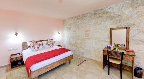 a bedroom with a bed and a desk and a stone wall at Dar Sitti Aziza in Bethlehem