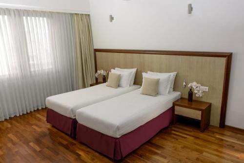 una habitación de hotel con una cama grande con sábanas blancas en City5 ROOMS & SUITES by LSA, en Skopje