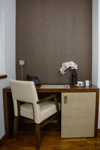 a desk with a white chair and a telephone at City5 ROOMS & SUITES by LSA in Skopje
