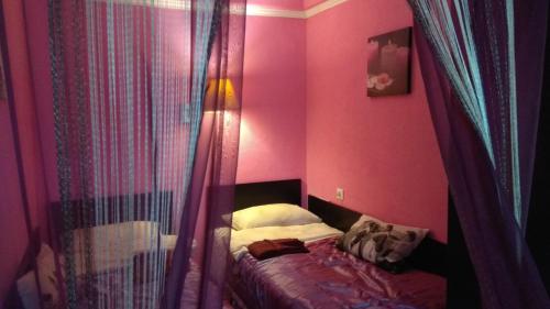 1 dormitorio con 1 cama con paredes y cortinas de color rosa en Apartment on Krylenko, en San Petersburgo