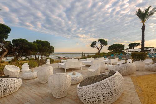 a patio with white chairs and a view of the ocean at Garden Playanatural - Adults Only in El Rompido