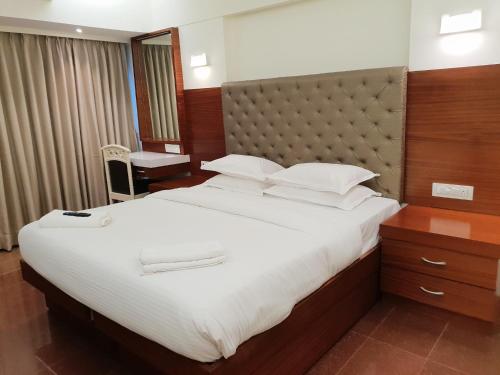 a hotel room with a large bed with white sheets at Hotel Milan International in Mumbai