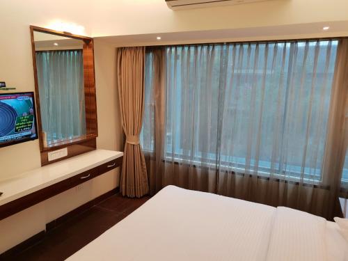 a bedroom with a bed and a television at Hotel Milan International in Mumbai