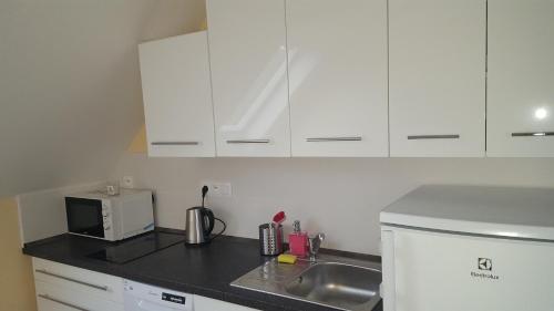 a kitchen with white cabinets and a sink and a microwave at Apartmá Helga in Lipova Lazne