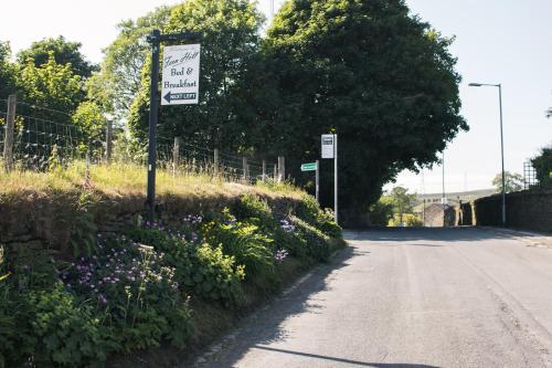 a street sign on the side of a road with flowers at Fernhill Hotel in Rochdale