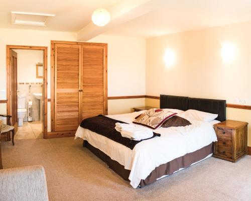 a bedroom with a large bed and a bathroom at Fernhill Bed and Breakfast in Rochdale