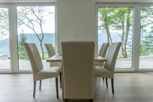 a dining room with a table and chairs and windows at Nature View House with Sauna in Tolmin