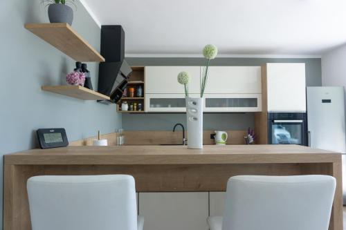 a kitchen with a wooden counter with white chairs at Nature View House with Sauna in Tolmin