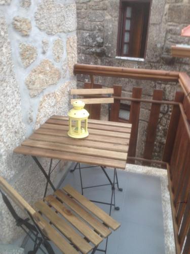 a wooden table with a yellow vase on a balcony at Casa de Bairros in Soajo
