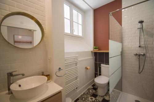 een badkamer met een wastafel, een toilet en een spiegel bij La Dame du Taur by Cocoonr in Toulouse